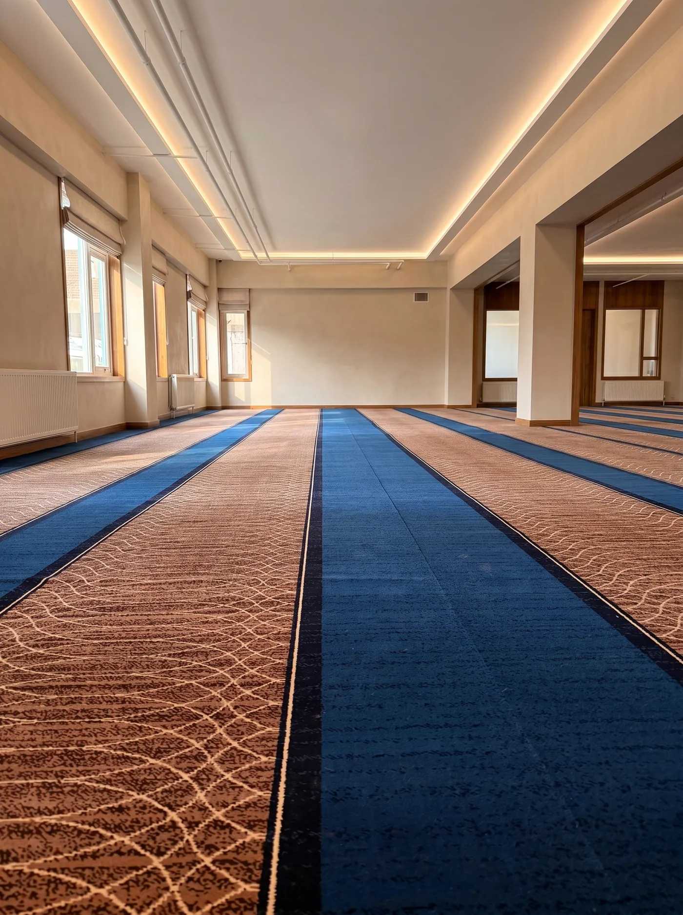 De vernieuwde gebedszaal met blauw tapijt in warm licht
