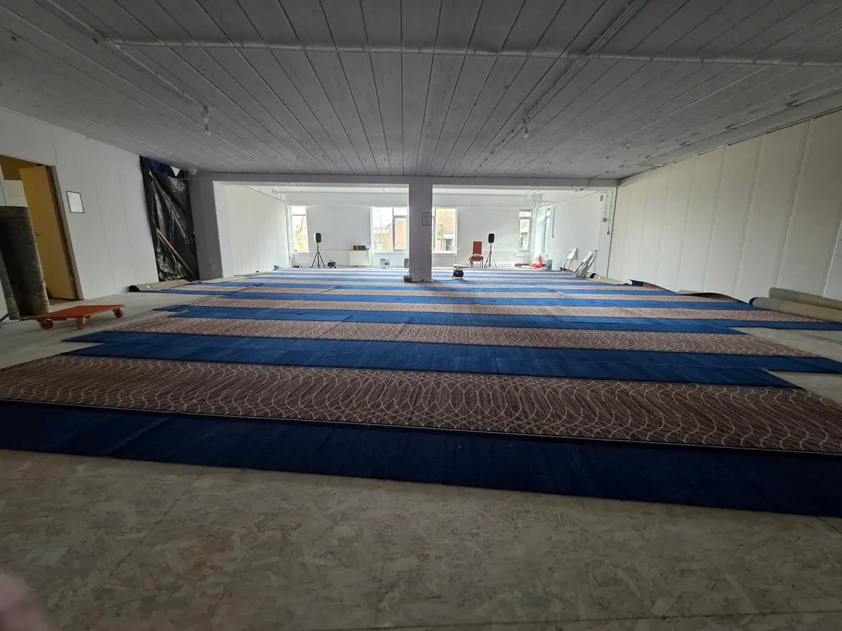 De gebedszaal met het volledig gelegde blauw-met-terracotta tapijt