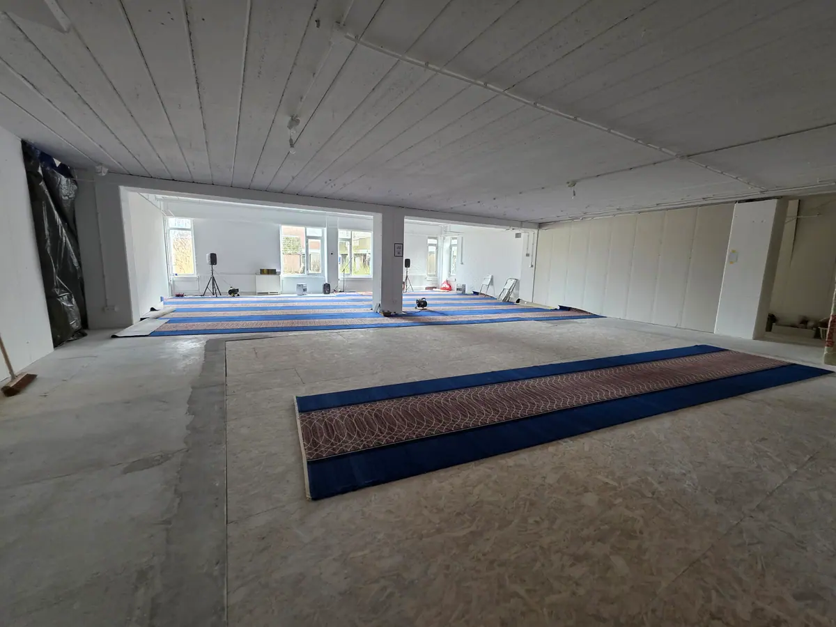 De lege zaal met de eerste tapijtbanen klaar om uit te rollen